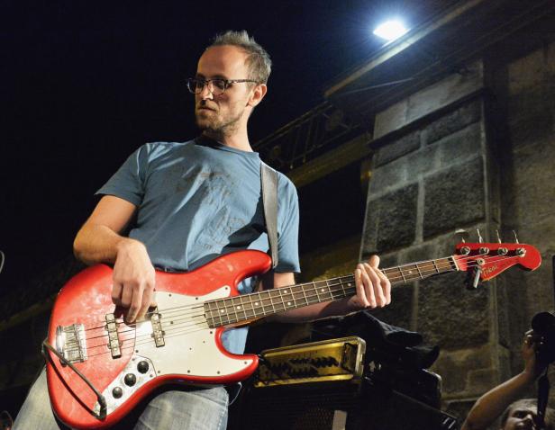 Ein Mann mit Brille spielt auf einer roten E-Gitarre.