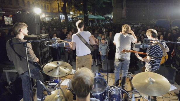 Eine Band spielt vor einem Publikum im Freien ein Konzert.