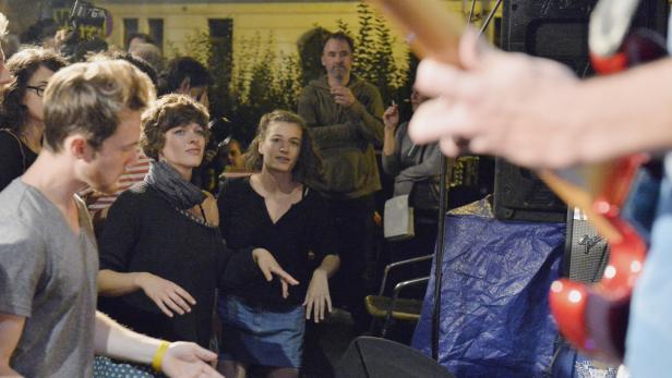 Eine Band spielt vor Publikum im Freien, während einige Leute tanzen.