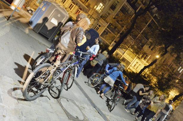 Eine Gruppe von Menschen steht mit Fahrrädern auf einem Bürgersteig vor einem Gebäude.
