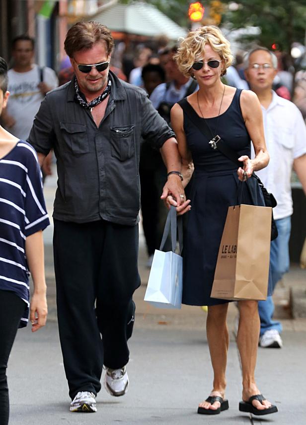 Meg Ryan und ein Mann mit Sonnenbrille gehen händchenhaltend eine Straße entlang.