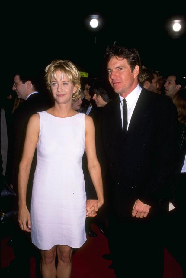 Meg Ryan und Dennis Quaid halten Händchen auf einem roten Teppich.