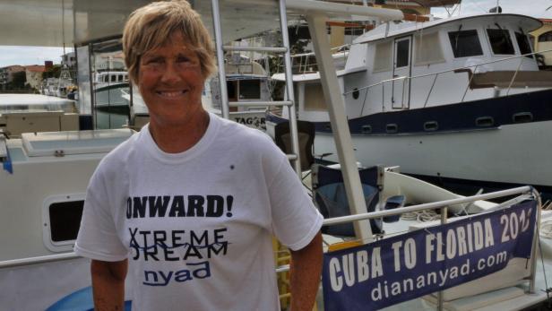 Diana Nyad steht vor einem Boot mit der Aufschrift „Cuba to Florida 2013“.