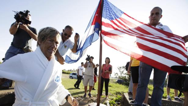 Diana Nyad nach ihrer Schwimmüberquerung von Kuba nach Florida, umgeben von Reportern und einer kubanisch-amerikanischen Flagge.