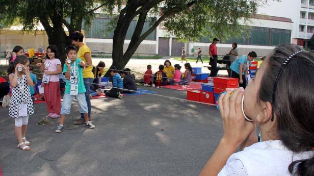Eine Gruppe Kinder spielt mit Dosen-Telefonen im Freien.