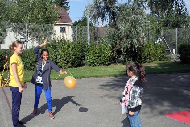 Eine junge Frau lässt einen Ballon an einer Schnur für ein kleines Mädchen schweben.