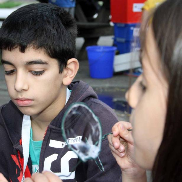 Ein Junge schaut zu, wie ein Mädchen Seifenblasen macht.