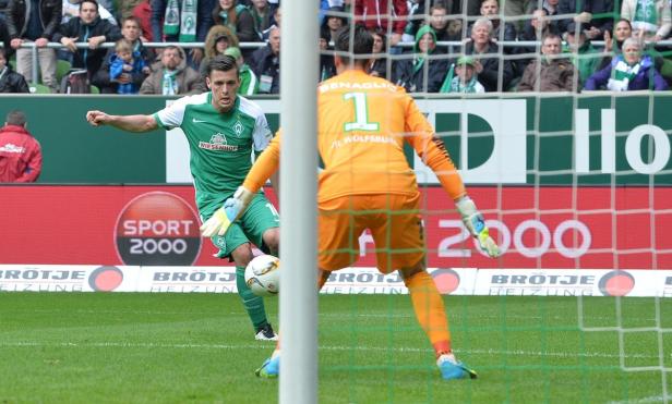 Ein Fußballspieler von Werder Bremen schießt auf das Tor, gehütet von Torwart Benaglio vom VfL Wolfsburg.