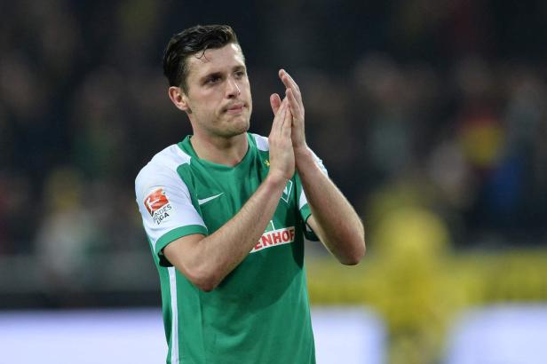 Ein Fußballspieler im grün-weißen Trikot klatscht in die Hände.