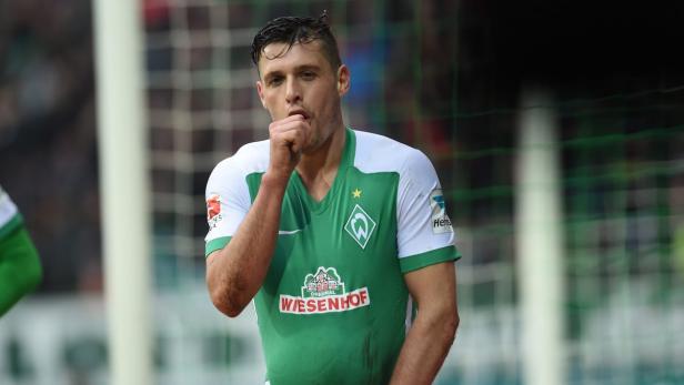 Ein Fußballspieler von Werder Bremen jubelt mit dem Finger im Mund.