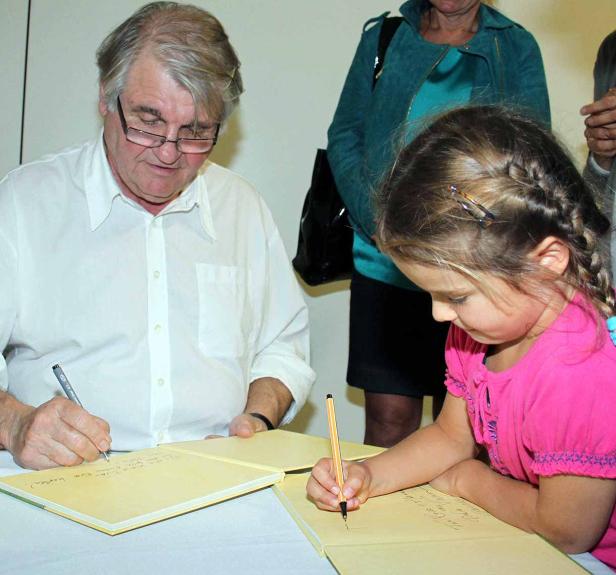 Ein Mann und ein junges Mädchen unterschreiben in einem Buch.