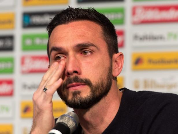 Ein Mann mit Bart wischt sich eine Träne aus dem Auge.