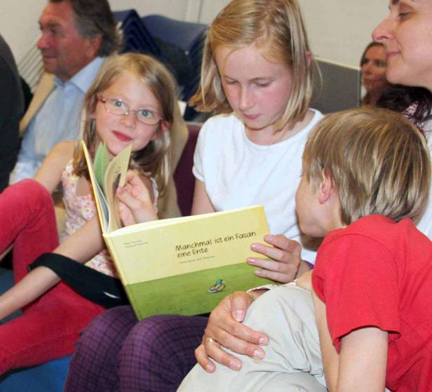 Eine Gruppe von Kindern liest gemeinsam ein Buch mit dem Titel „Manchmal ist ein Fasan eine Ente“.