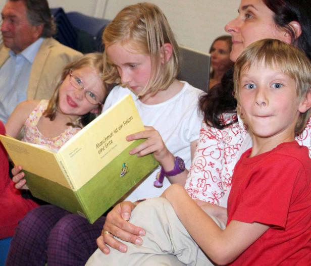 Eine Gruppe von Kindern liest gemeinsam ein Buch mit dem Titel „Manchmal ist ein Fasan eine Ente“.
