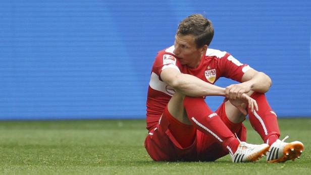 Ein Fußballspieler des VfB Stuttgart sitzt enttäuscht auf dem Rasen.