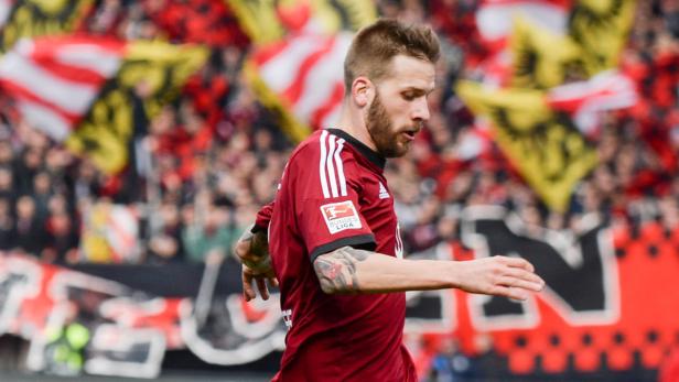 Ein Fußballspieler in rotem Trikot vor einer Zuschauermenge.