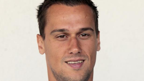 Porträt eines lächelnden Mannes mit braunen Haaren und Augen.