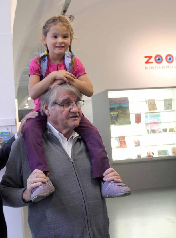 Ein Mann trägt ein junges Mädchen mit Zöpfen huckepack vor dem Zoom Kindermuseum.