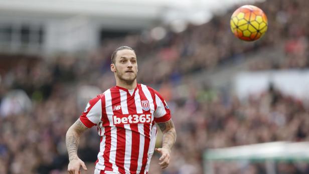 Ein Fußballspieler im rot-weiß gestreiften Trikot mit einem Ball in der Luft.
