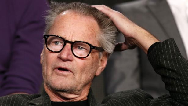Ein Mann mit Brille und grauem Haar kratzt sich am Kopf.