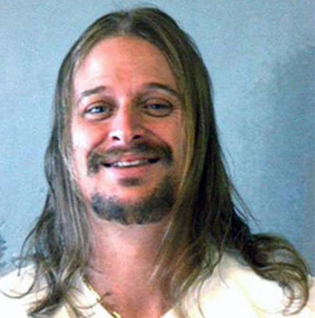 Ein Porträt von Kid Rock mit langen Haaren und Bart, der lächelt.