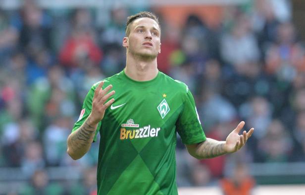 Ein Fußballspieler im grün-weißen Trikot von Werder Bremen gestikuliert auf dem Spielfeld.