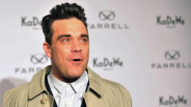 Porträt von Robbie Williams vor einem Hintergrund mit Logos.