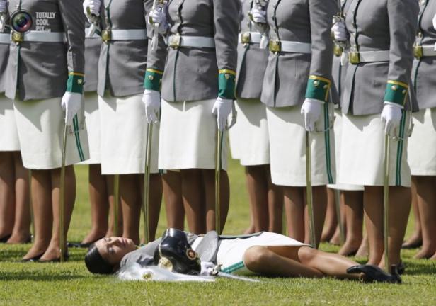 Eine Kadettin liegt ohnmächtig auf dem Rasen, während andere in Formation stehen.