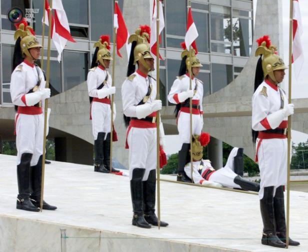 Eine Gruppe von Gardesoldaten in Paradeuniform steht Wache, einer liegt am Boden.