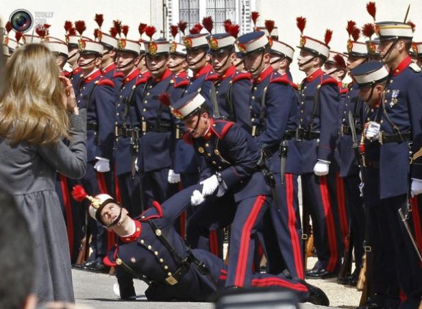 Ein Soldat fällt während einer Parade um, während ein anderer ihm hilft, sich aufzurappeln.
