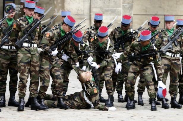 Eine Gruppe von Soldaten in Uniform hilft einem gefallenen Kameraden aufzustehen.