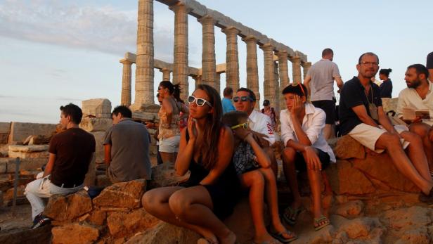Tempel des Poseidon südöstlich von Athen: Schwitzen unter der hellenischen Sonne Eine Gruppe von Menschen sitzt vor den Säulen des Poseidontempels am Kap Sounion.
