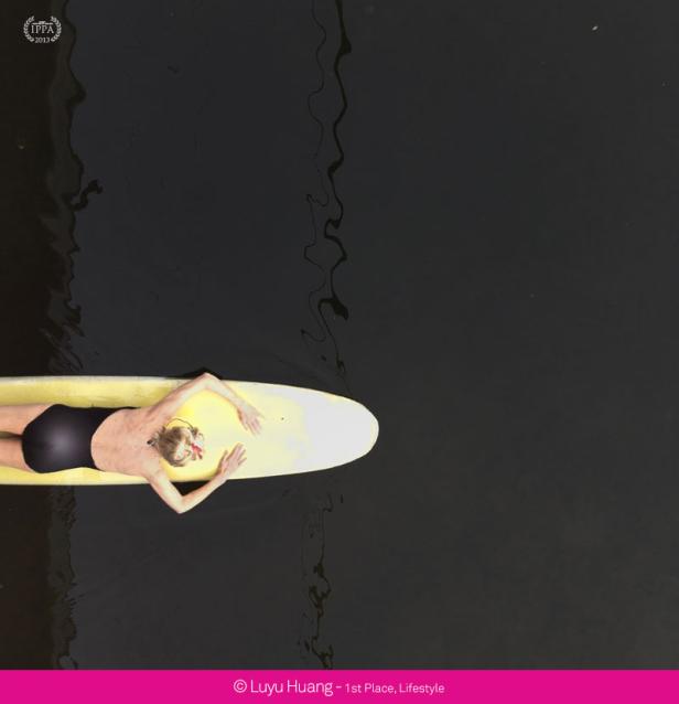 Eine Frau liegt auf einem Surfbrett auf dem dunklen Wasser.