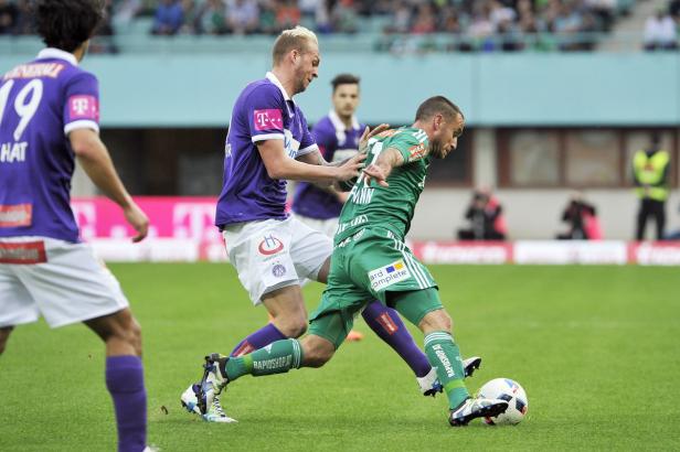Zwei Fußballspieler kämpfen um den Ball auf dem Spielfeld.