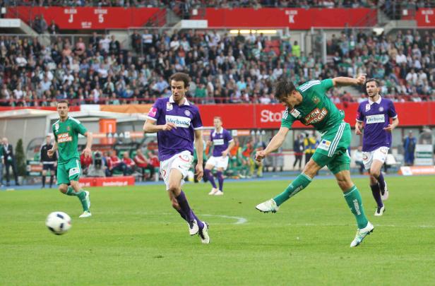 Ein Fußballspieler in Grün schießt den Ball während eines Spiels.