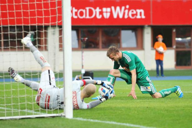 Ein Fußballspieler kniet auf dem Rasen, während ein Torwart im Tor liegt.