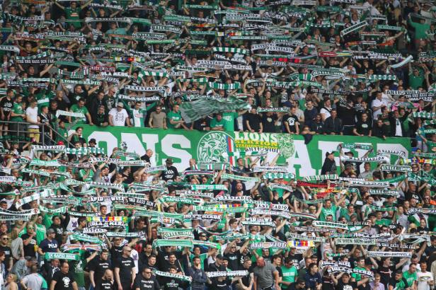 Eine große Menschenmenge, die Schals des SK Rapid Wien im Stadion hochhält.
