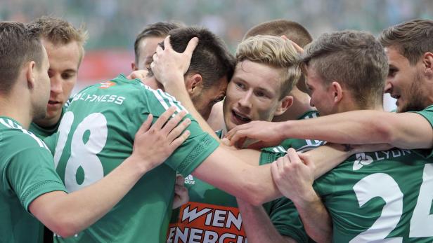 Eine Gruppe von Handballspielern in grünen Trikots umarmt sich jubelnd.