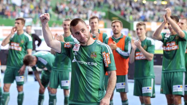 Ein Fußballspieler jubelt mit erhobener Faust, umgeben von seinen Teamkollegen.