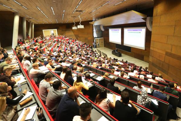 Ein voll besetzter Hörsaal mit Studierenden während einer Vorlesung.