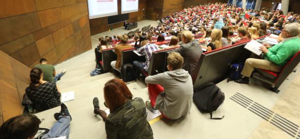 Ein voll besetzter Hörsaal mit Studierenden während einer Vorlesung.