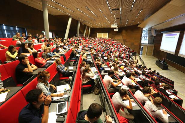 Ein voll besetzter Hörsaal mit Studierenden während einer Vorlesung.