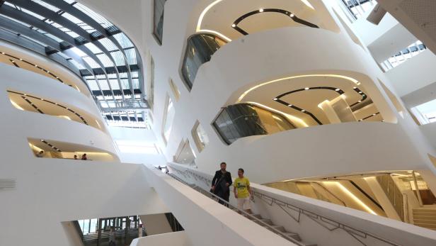 Zwei Männer gehen die Treppe in einem modernen, weißen Gebäude hinunter.