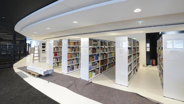 Blick in eine Bibliothek mit weißen Bücherregalen und vorbereiteten Baumaterialien.