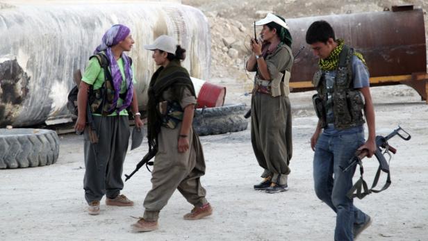 Vier bewaffnete Personen in Militärkleidung stehen im Freien.