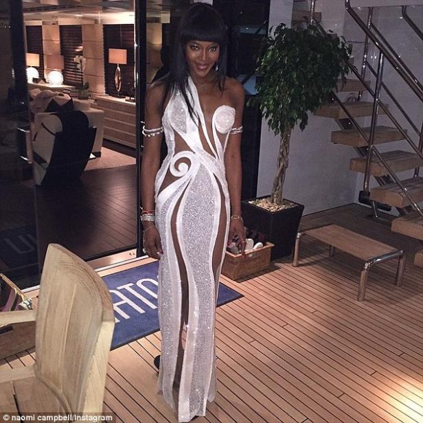 Naomi Campbell in einem weißen, glitzernden Kleid auf einer Yacht.