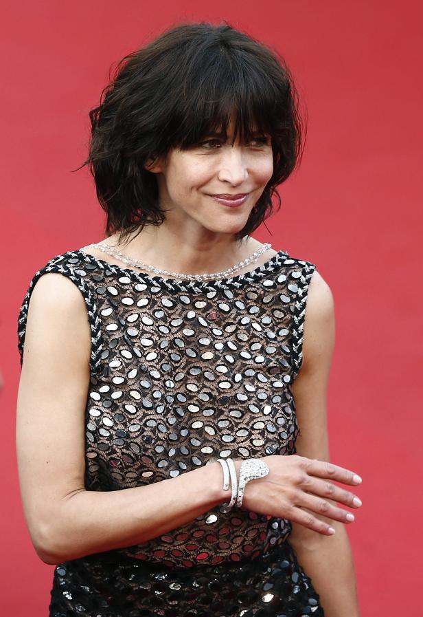 Sophie Marceau auf einem roten Teppich in einem schwarzen Kleid mit Pailletten.
