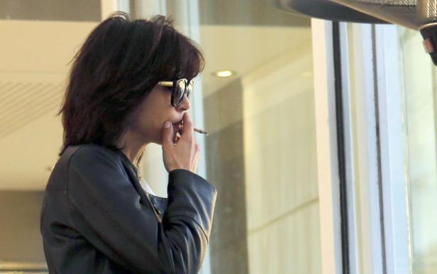 Eine Frau mit Sonnenbrille raucht eine Zigarette.