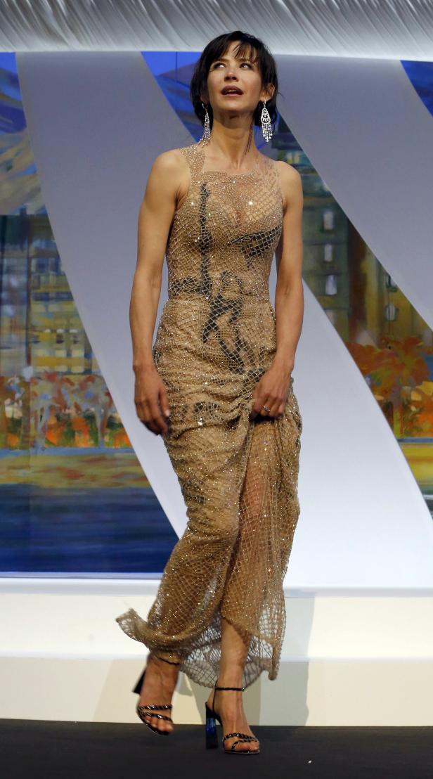 Sophie Marceau in einem goldenen, netzartigen Kleid auf einer Bühne.