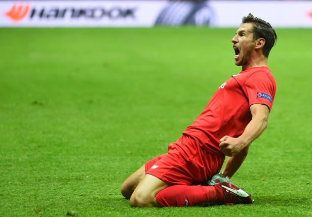 Ein Fußballspieler in roter Uniform jubelt auf dem Rasen.